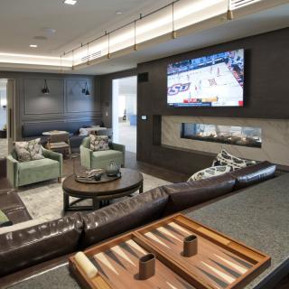 A modern lounge area featuring a large TV, comfortable seating, and a game board on the table.