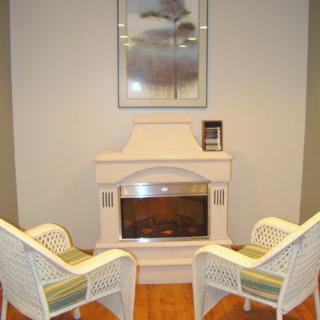 A cozy living room setting with a fireplace and two white wicker chairs.
