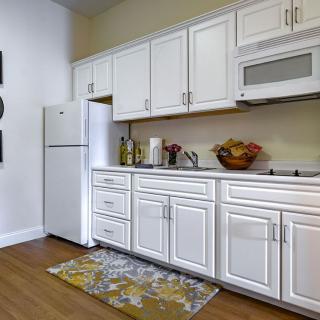 A modern kitchen with white cabinets, a refrigerator, and a microwave.
