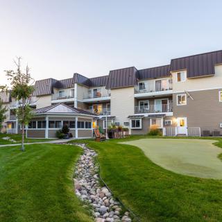 A modern apartment building with a well-maintained lawn and outdoor patio area.