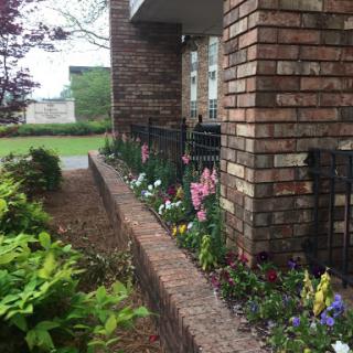A beautifully landscaped garden with a variety of colorful flowers along a brick wall.