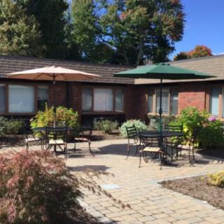 A peaceful outdoor patio area with tables, chairs, and umbrellas set against a brick building.