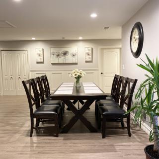 A modern dining room features a sleek wooden table surrounded by chairs, with minimalist decor and greenery.