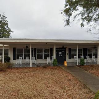 A single-story house with a spacious front porch lined with rocking chairs.