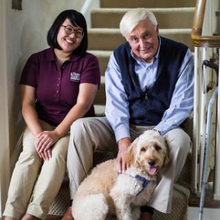 A joyful moment captured with an elderly man, a woman, and their cheerful dog seated on the stairs.