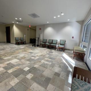 An empty waiting room with chairs lined against the wall and tiled flooring.