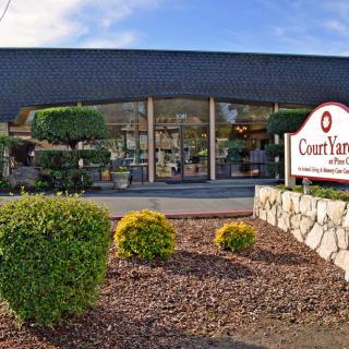 A well-maintained storefront with manicured bushes and a prominent sign at the entrance.
