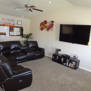 A cozy living room with a leather couch, large TV, and modern decor.