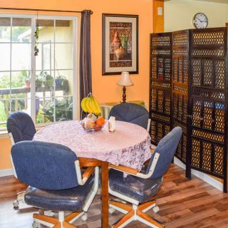 A cozy dining area featuring a round table with chairs, decorated with fruits and surrounded by warm decor.