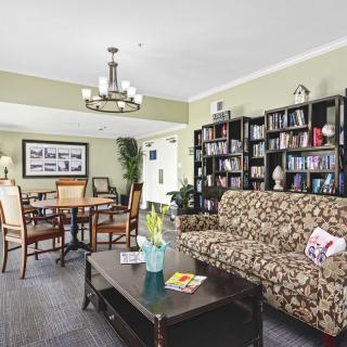 A cozy living room with a patterned sofa, bookshelves, and a dining area under a chandelier.