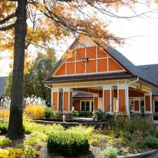 A beautifully designed building surrounded by vibrant autumn foliage and well-maintained gardens.