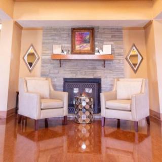 A cozy living room with two chairs flanking a fireplace, featuring elegant decor and warm wooden flooring.