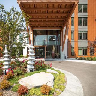 A modern building entrance with wooden overhang and landscaped gardens.