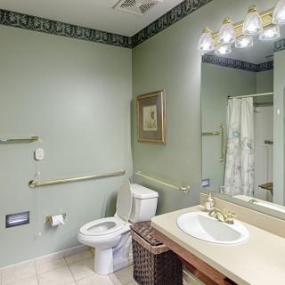 A well-lit bathroom featuring a toilet, sink, and shower area.