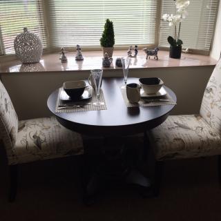 A small dining table set for two with decorative accents by the window.