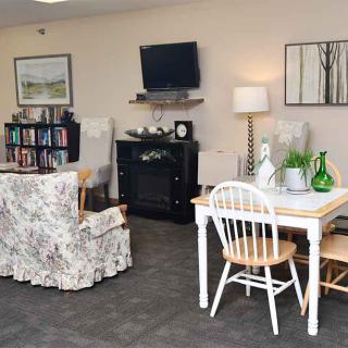 A cozy living room with a table and chairs, a bookshelf, a television, and decorative items.
