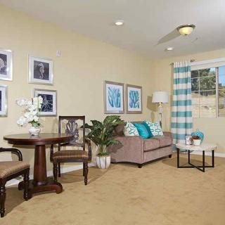A cozy living room with a sofa, table, chairs, and decorative artwork on the walls.