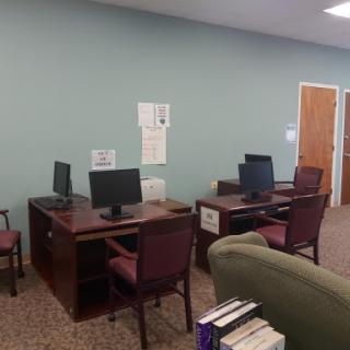 A quiet office space featuring desks with computers and a bookshelf.