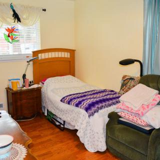 A cozy bedroom with a single bed, armchair, and side table.