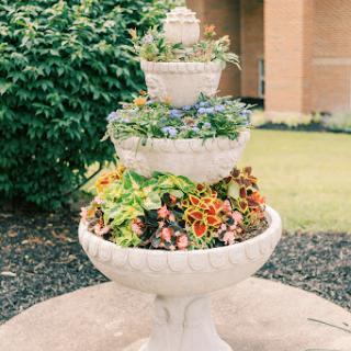 A beautifully arranged tiered fountain planter filled with vibrant flowers, adding charm to the garden.
