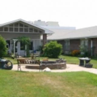 A well-maintained garden area with a circular patio and outdoor seating in front of a house.
