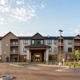 A modern residential apartment building with a large entrance and clear skies.
