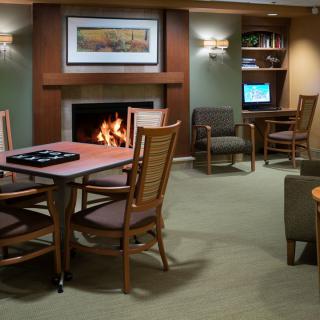 A cozy lounge area with a fireplace, seating, and computer stations.