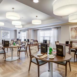 A modern dining area with neatly arranged tables and chairs, featuring stylish lighting and decor.