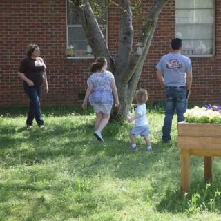 A family enjoys a sunny day outside near a brick building.