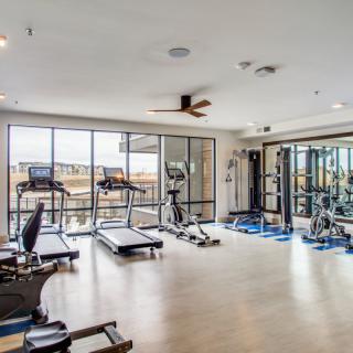 A modern gym with various exercise equipment including treadmills, a stationary bike, and weights.