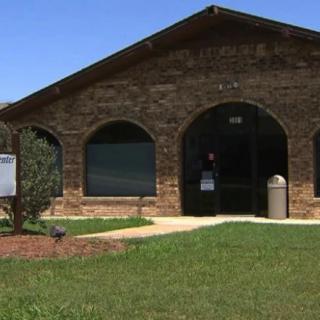 A brick building with large arched windows and a grassy lawn in front.