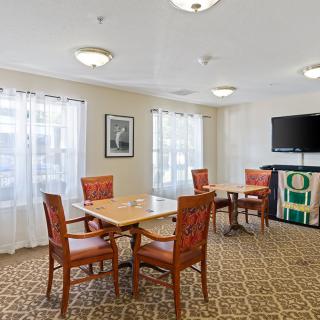 A well-lit dining area with a table, chairs, and a television.