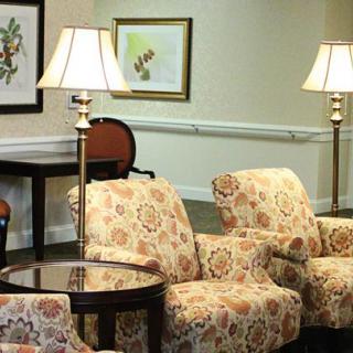 A cozy living room setup featuring patterned chairs, a glass-top table, and floor lamps.