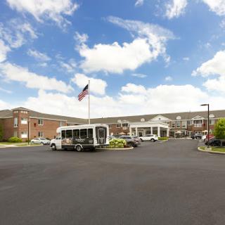 An exterior view of a hotel with a bus and flag in the foreground, under a partly cloudy sky.