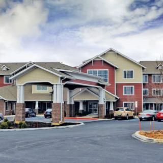 A mid-sized hotel with an inviting entrance and a parking lot under a cloudy sky.