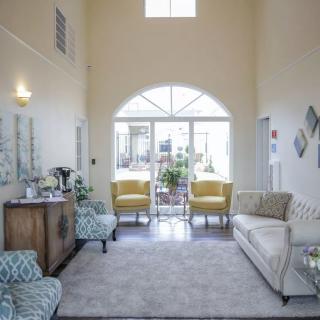 A spacious living room with elegant furniture, featuring a sofa, chairs, and large windows that let in natural light.