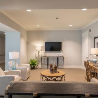 A modern living room featuring a stylish seating area with neutral tones, complete with a television and decorative accents.