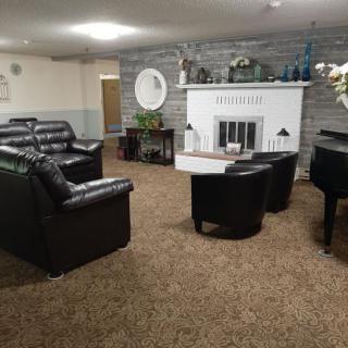 A cozy living room featuring leather sofas, a piano, and a fireplace.