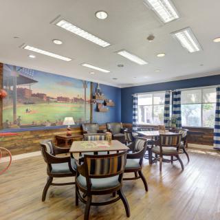 A cozy dining area with wooden floors, tables and chairs, featuring a colorful mural on the wall.