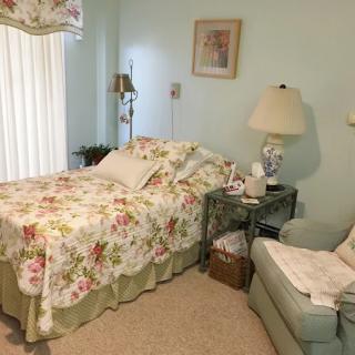 A cozy bedroom with floral bedding and a lamp on the nightstand.