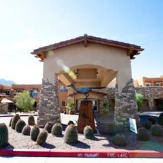 An entrance of a building featuring stone pillars and desert landscaping.