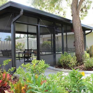 A serene screened porch surrounded by lush greenery, perfect for relaxation.