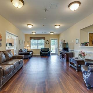 A spacious living room featuring leather sofas, hardwood flooring, and a television.