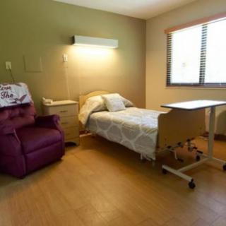 A hospital room with a bed, armchair, and medical equipment.