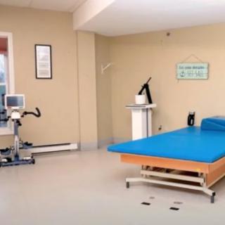 A rehabilitation room equipped with exercise equipment and a treatment bed for physical therapy.