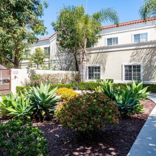A well-maintained garden with lush plants in front of a residential building.