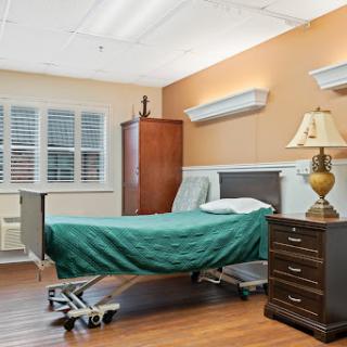 A cozy and well-lit patient room with a hospital bed, elegant furniture, and a calming color palette.