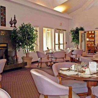 A cozy dining room with elegant decor, featuring tables and chairs arranged around a fireplace.