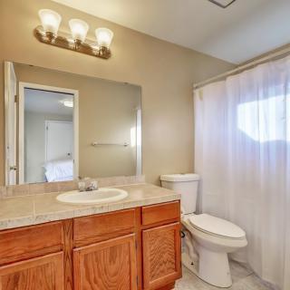 A well-lit bathroom featuring a wooden vanity, sink, and toilet with a white shower curtain.