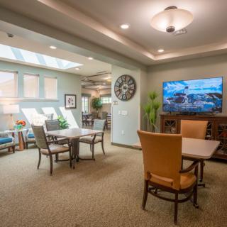 A cozy living room with comfortable seating, a large television, and skylights for natural lighting.